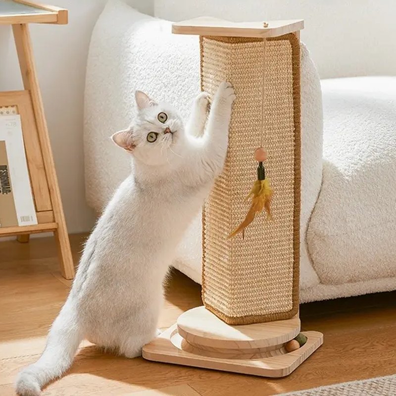 A white cat scratching the Hush Corner Scratcher, Play version, beside a cream couch